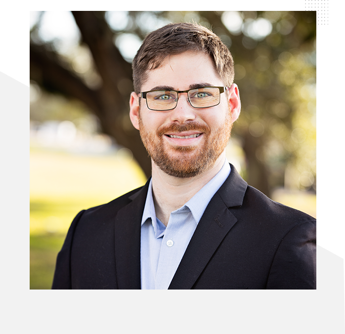 A man in glasses and suit jacket smiling for the camera.