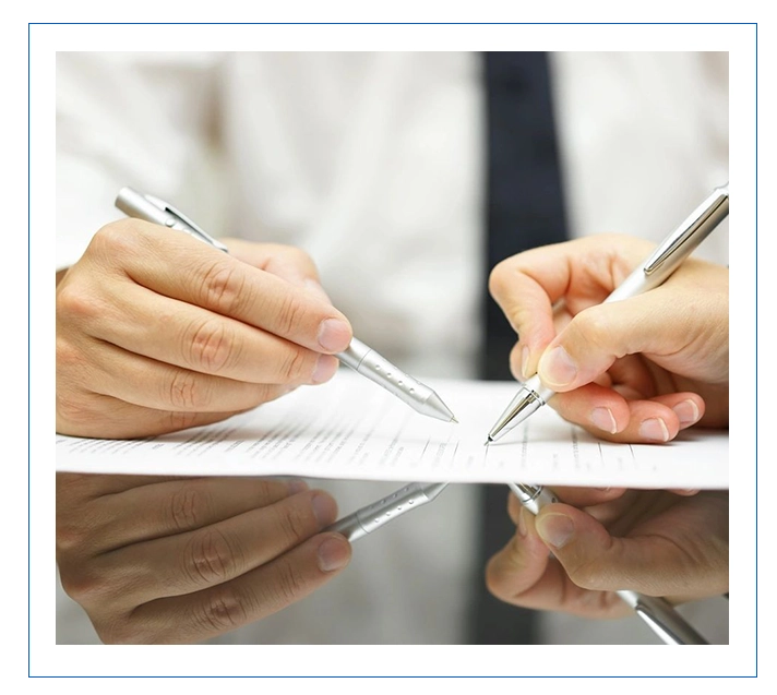 Two people are writing on a piece of paper.